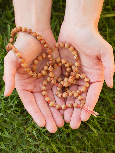 Outstretched hands holding wooden prayer beads