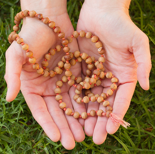 Outstretched hands holding wooden prayer beads